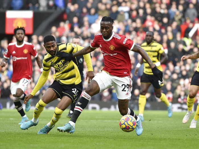 Watford's Emmanuel Dennis vies for the ball with Manchester United's Aaron Wan-Bissaka, center, during the English Premier League soccer match between Manchester United and Watford at Old Trafford in Manchester, England, Saturday, Feb. 26, 2022. (AP Photo/Rui Vieira)