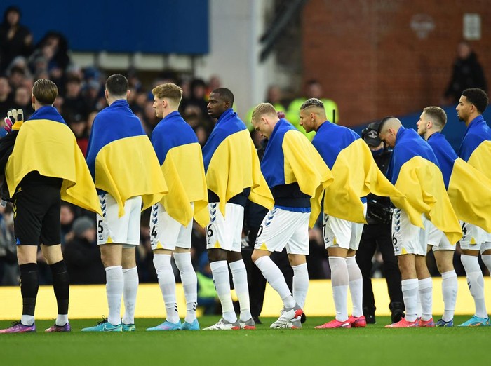 Soccer Football - Premier League - Everton v Manchester City - Goodison Park, Liverpool, Britain - February 26, 2022 Everton players are draped in the Ukraine flags as they line up before the match REUTERS/Peter Powell EDITORIAL USE ONLY. No use with unauthorized audio, video, data, fixture lists, club/league logos or 'live' services. Online in-match use limited to 75 images, no video emulation. No use in betting, games or single club /league/player publications.  Please contact your account representative for further details.