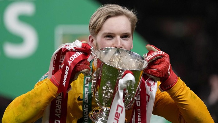 Liverpools goalkeeper Caoimhin Kelleher poses with the trophy after winning the English League Cup final soccer match between Chelsea and Liverpool at Wembley stadium in London, Sunday, Feb. 27, 2022. Liverpool won a penalty shootout 11-10 after the match ended tied 0-0. (AP Photo/Alastair Grant)