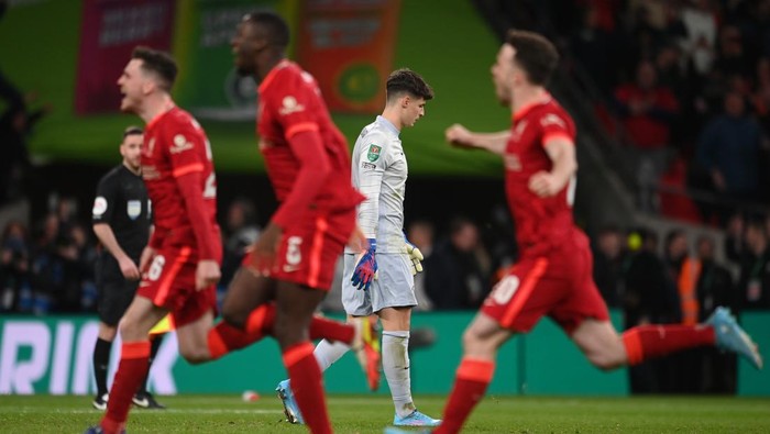 LONDON, ENGLAND - FEBRUARY 27: Kepa Arrizabalaga of Chelsea looks dejected after missing the deciding penalty in the penalty shoot out as players of Liverpool celebrate following the Carabao Cup Final match between Chelsea and Liverpool at Wembley Stadium on February 27, 2022 in London, England. (Photo by Michael Regan/Getty Images)