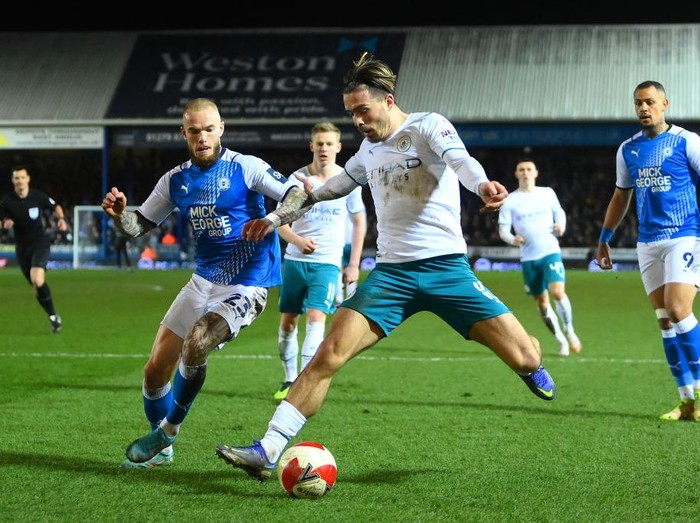 PETERBOROUGH, ENGLAND - MARCH 01: Jack Grealish of Manchester City is challenged by Joe Ward of Peterborough United during the Emirates FA Cup Fifth Round match between Peterborough United and Manchester City at ABAX Stadium on March 01, 2022 in Peterborough, England. (Photo by Laurence Griffiths/Getty Images)