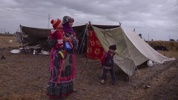 A Bedouin nomad woman, Thanaa Abeda, carries her child as a rain storm approaches outside her tent during a stay along a highway road, which leads to the capital city of Cairo, on Egypt's Nile Delta province of Kafr El-Sheikh, Egypt February 19, 2022. Picture taken February 19, 2022. REUTERS/Hadeer Mahmoud NO RESALES. NO ARCHIVES.