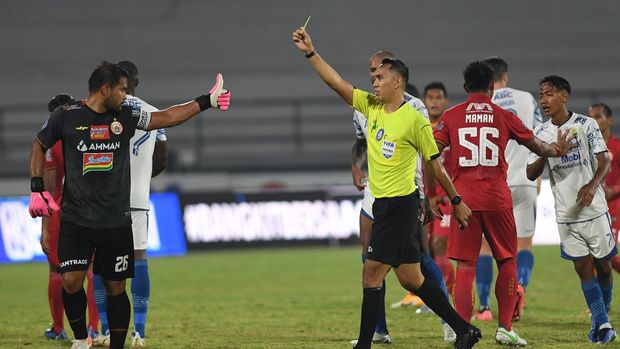 Wasit Fariq Hitaba (ketiga kanan) memberikan kartu kuning kepada penjaga gawang Persija Jakarta Andritany (kiri) setelah terlibat keributan dengan pemain Persib Bandung dalam pertandingan sepak bola Liga 1 di Stadion I Wayan Dipta, Gianyar, Bali, Selasa (1/3/2022). Persib Bandung memenangkan pertandingan dengan skor 2-0. ANTARA FOTO/Nyoman Budhiana/rwa.