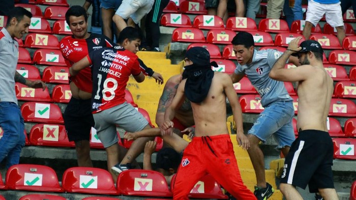 Supporters of Atlas fight with supporters of Queretaro during the Mexican Clausura tournament football match between Queretaro and Atlas at Corregidora stadium in Queretaro, Mexico on March 5, 2022. - A match between Mexican football clubs was called off March 5, 2022 after violence by opposing fans spilled onto the field. The game between Queretaro and Atlas at La Corregidora stadium in the city of Queretaro  -- the ninth round of the 2022 Clausura football tournament -- was in its 63rd minute when fights between opposing fans broke out. (Photo by EDUARDO GOMEZ / AFP)