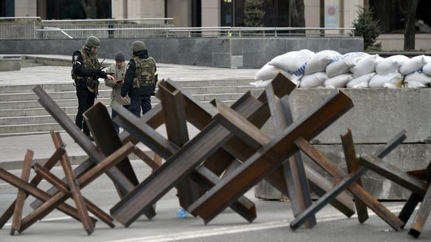 Ukrainian police officers check the documents of a passer-by next to anti-tank obstacles in the center of Kyiv on March 7, 2022. (Photo by Sergei SUPINSKY / AFP)