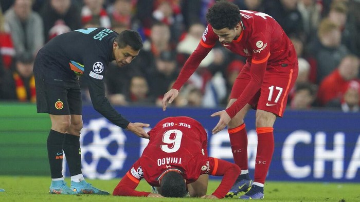 Liverpools Thiago, center, grimaces in pain after a tackle by Inter Milans Alexis Sanchez, left, during the Champions League, round of 16, second leg soccer match between Liverpool and Inter Milan at Anfield stadium in Liverpool, England, Tuesday, March 8, 2022. (AP Photo/Jon Super)