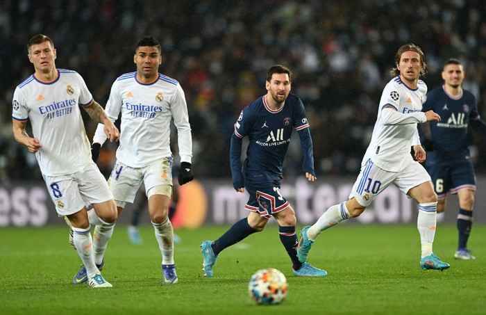 PARIS, FRANCE - FEBRUARY 15: Lionel Messi of Paris Saint-Germain runs with the ball from Toni Kroos, Casemiro and Luka Modric of Real Madrid during the UEFA Champions League Round Of Sixteen Leg One match between Paris Saint-Germain and Real Madrid at Parc des Princes on February 15, 2022 in Paris, France. (Photo by Shaun Botterill/Getty Images)