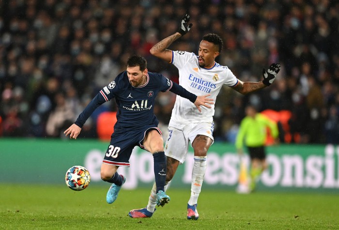 PARIS, FRANCE - FEBRUARY 15: Lionel Messi of Paris Saint-Germain is challenged by Eder Militao of Real Madrid during the UEFA Champions League Round Of Sixteen Leg One match between Paris Saint-Germain and Real Madrid at Parc des Princes on February 15, 2022 in Paris, France. (Photo by Shaun Botterill/Getty Images)