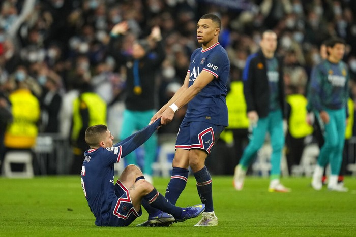 PSGs Kylian Mbappe helps teammate Marco Verratti get up after their loss in the Champions League, round of 16, second leg soccer match between Real Madrid and Paris Saint-Germain at the Santiago Bernabeu stadium in Madrid, Spain, Wednesday, March 9, 2022. (AP Photo/Manu Fernandez)