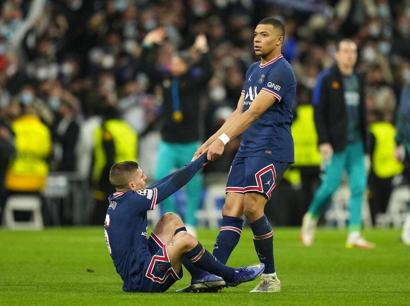 PSG's Kylian Mbappe helps teammate Marco Verratti get up after their loss in the Champions League, round of 16, second leg soccer match between Real Madrid and Paris Saint-Germain at the Santiago Bernabeu stadium in Madrid, Spain, Wednesday, March 9, 2022. (AP Photo/Manu Fernandez)