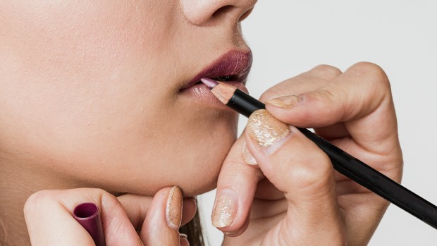 Memakai lip liner agar bibir terlihat penuh untuk makeup cantik perempuan usia 40-an.