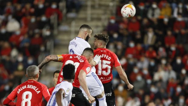 Real Madrid's Karim Benzema, centre, jumps to head home his side's third goal during a Spanish La Liga soccer match between Mallorca and Real Madrid in Palma de Mallorca, Spain, Monday, March 14, 2022. (AP Photo/Francisco Ubilla)