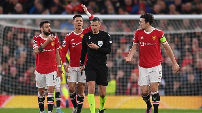 MANCHESTER, ENGLAND - MARCH 15: Bruno Fernandes, Cristiano Ronaldo and Harry Maguire of Manchester United speak to the Referee Slavko Vincic after Renan Lodi of Atletico Madrid (not pictured) scored their sides first goal during the UEFA Champions League Round Of Sixteen Leg Two match between Manchester United and Atletico Madrid at Old Trafford on March 15, 2022 in Manchester, England. (Photo by Michael Regan/Getty Images)