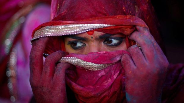 A girl covers her face as she takes part in the religious festival of Holi inside a temple in Nandgaon village, in the state of Uttar Pradesh, India, March 12, 2022. REUTERS/Adnan Abidi