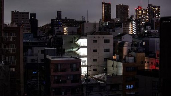 A woman shops in a store in a residential area during a power outage in Koto district in Tokyo on March 16, 2022, after a powerful 7.3-magnitude quake jolted east Japan. (Photo by Philip FONG / AFP)