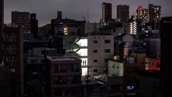 JAPAN-EARTHQUAKE A woman shops in a store in a residential area during a power outage in Koto district in Tokyo on March 16, 2022, after a powerful 7.3-magnitude quake jolted east Japan. (Photo by Philip FONG / AFP)