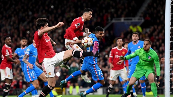 MANCHESTER, ENGLAND - MARCH 15: Cristiano Ronaldo and Harry Maguire of Manchester United stretch for the ball during the UEFA Champions League Round Of Sixteen Leg Two match between Manchester United and Atletico Madrid at Old Trafford on March 15, 2022 in Manchester, England. (Photo by Shaun Botterill/Getty Images)