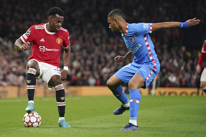 Manchester Uniteds Anthony Elanga, left, and Atletico Madrids Renan Lodi, right, battle for the ball during the Champions League round of 16, second leg soccer match between Manchester United and Atletico Madrid at Old Trafford, Manchester, England, Tuesday, March 15, 2022. (AP Photo/Dave Thompson)
