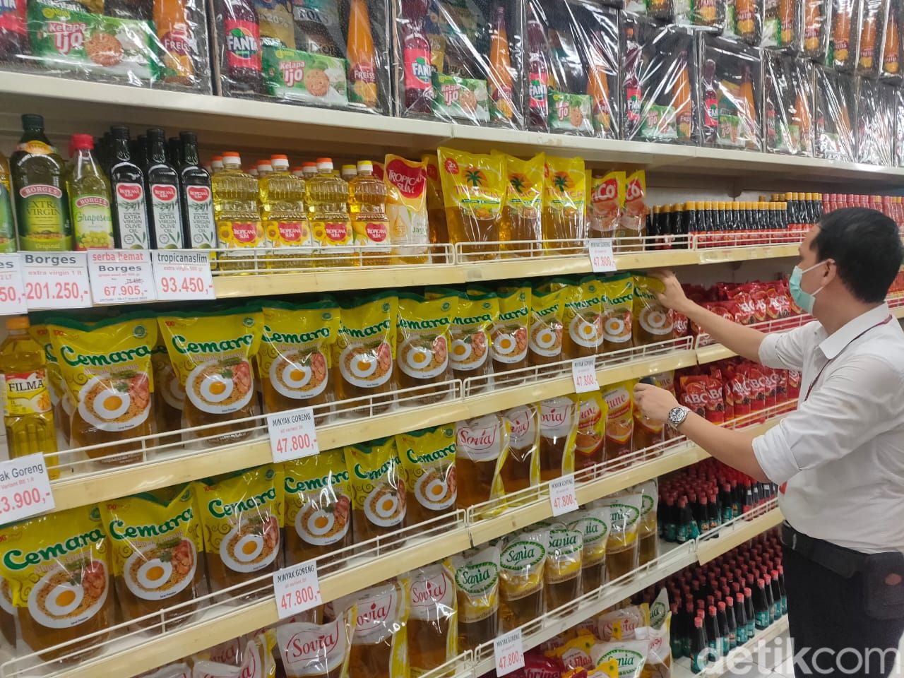 Karyawan toserba sedang merapihkan minyak goreng kemasan.