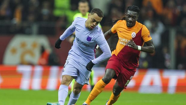 Barcelona's Sergino Dest, left, vies for the ball with Galatasaray's Bafetimbi Gomis during the Europa League round of 16 second leg soccer match between Galatasaray and Barcelona in Istanbul, Turkey, Thursday, March 17, 2022. (AP Photo)