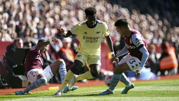 Aston Villa's Ashley Young, left, and Philippe Coutinho combine to tackle Arsenal's Bukayo Saka, center, during the English Premier League soccer match between Aston Villa and Arsenal at Villa Park, Birmingham, England, Saturday, March 19, 2022. (Nick Potts/PA via AP)