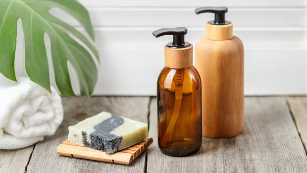 Wooden and glass bathroom accessories without label. Soap bar dish and liquid soap pump dispensers on wooden background