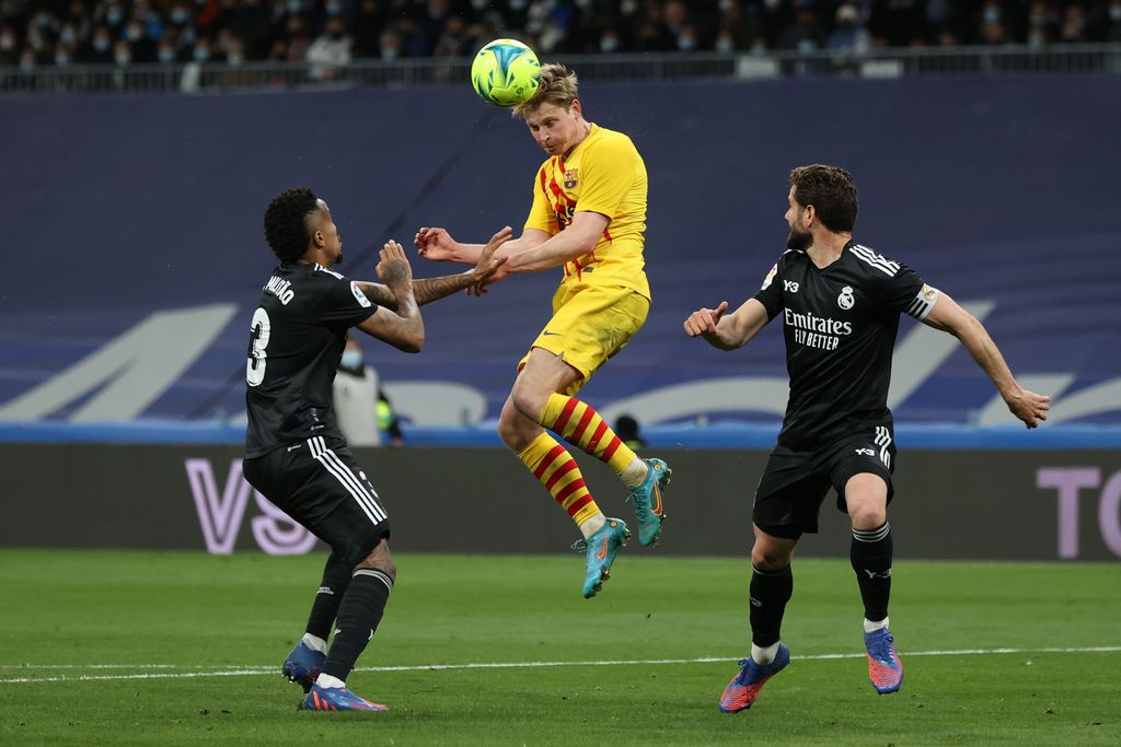 MADRID, SPAIN - MARCH 20: Frenkie De Jong <of FC Barcelona wins the header before Eder Gabriel Militao (L) of Real Madrid CF and his teammate Nacho Fernandez (R) during the LaLiga Santander match between Real Madrid CF and FC Barcelona at Estadio Santiago Bernabeu on March 20, 2022 in Madrid, Spain. (Photo by Gonzalo Arroyo Moreno/Getty Images)