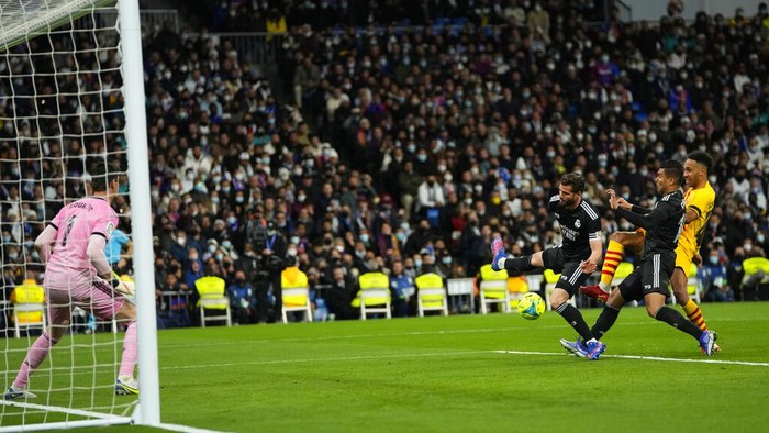 Barcelona's Pierre-Emerick Aubameyang, right, scores his side's fourth goal in front Real Madrid's goalkeeper Thibaut Courtois during a Spanish La Liga soccer match between Rial Madrid and FC Barcelona at the Santiago Bernabeu stadium in Madrid, Spain, Sunday, March 20, 2022. (AP Photo/Manu Fernandez)