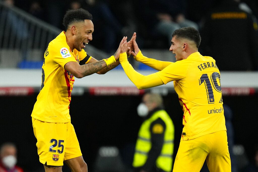 Barcelona's Pierre-Emerick Aubameyang, right, scores his side's fourth goal in front Real Madrid's goalkeeper Thibaut Courtois during a Spanish La Liga soccer match between Rial Madrid and FC Barcelona at the Santiago Bernabeu stadium in Madrid, Spain, Sunday, March 20, 2022. (AP Photo/Manu Fernandez)