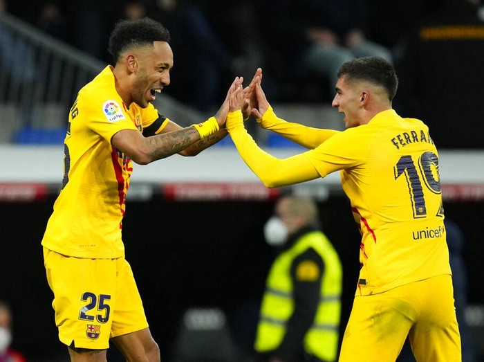 Barcelona's Pierre-Emerick Aubameyang, right, scores his side's fourth goal in front Real Madrid's goalkeeper Thibaut Courtois during a Spanish La Liga soccer match between Rial Madrid and FC Barcelona at the Santiago Bernabeu stadium in Madrid, Spain, Sunday, March 20, 2022. (AP Photo/Manu Fernandez)