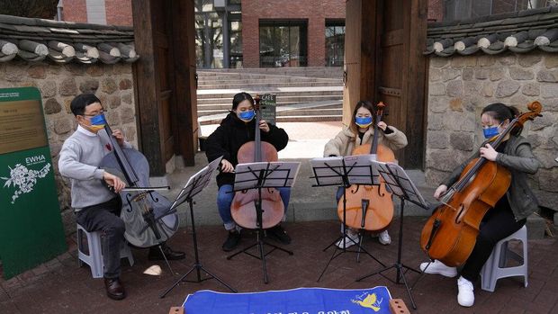A professor and students from Ewha Womans University wearing masks in the colors of Ukraine's flag hold an outdoor mini-concert for peace in Seoul, South Korea, Monday, March 21, 2022. (AP Photo/Lee Jin-man)
