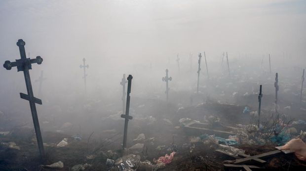 EDITORS NOTE: Graphic content / Crosses are pictured under smoke from a garbage in the cemetery of Mykolaiv, southern Ukraine, on March 21, 2022. (Photo by BULENT KILIC / AFP)