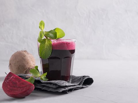 Glass of fresh beetroot juice garnish mint on grey table. Close up.