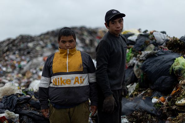 LUJAN, ARGENTINA - MARCH 23: Men work as garbage falls from a garbage truck to sort and sell its residues on March 23, 2022 in Lujan, Argentina. Despite the official announcements of a plan to reconvert the biggest garbage dump of Argentina into a recycling and waste treatment center, the surrounding areas of Lujan, in the outskirts of the city of Buenos Aires, continue to be hit pollution. While some residents are sceptical on the viability of the project, funded by the Inter-American Development Bank, others worry about a potential loss of their source of income. An estimate of 150 families struggle to make a living collecting rubbish from this open-air dump of over 12 hectares where 120 tons of waste are thrown, feeding mountains of rubbish up to 30 meters. (Photo by Tomas Cuesta/Getty Images)
