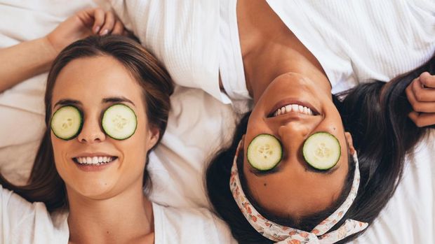 Shot of two girlfriends relaxing with cucumber slices on their eyes