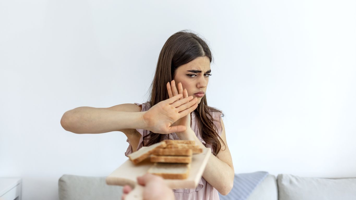 Cropped shot of a young woman on a gluten free diet is saying no thanks to white bread. Woman refusing to eat white bread. Gluten intolerance concept. Health care and medicine concept. Copy space.