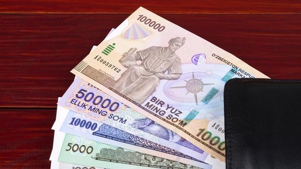Uzbekistan money in the black wallet on a wooden background