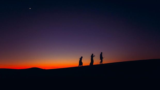 ilustrasi ramadan Arabs walking over Sand dune during dusk