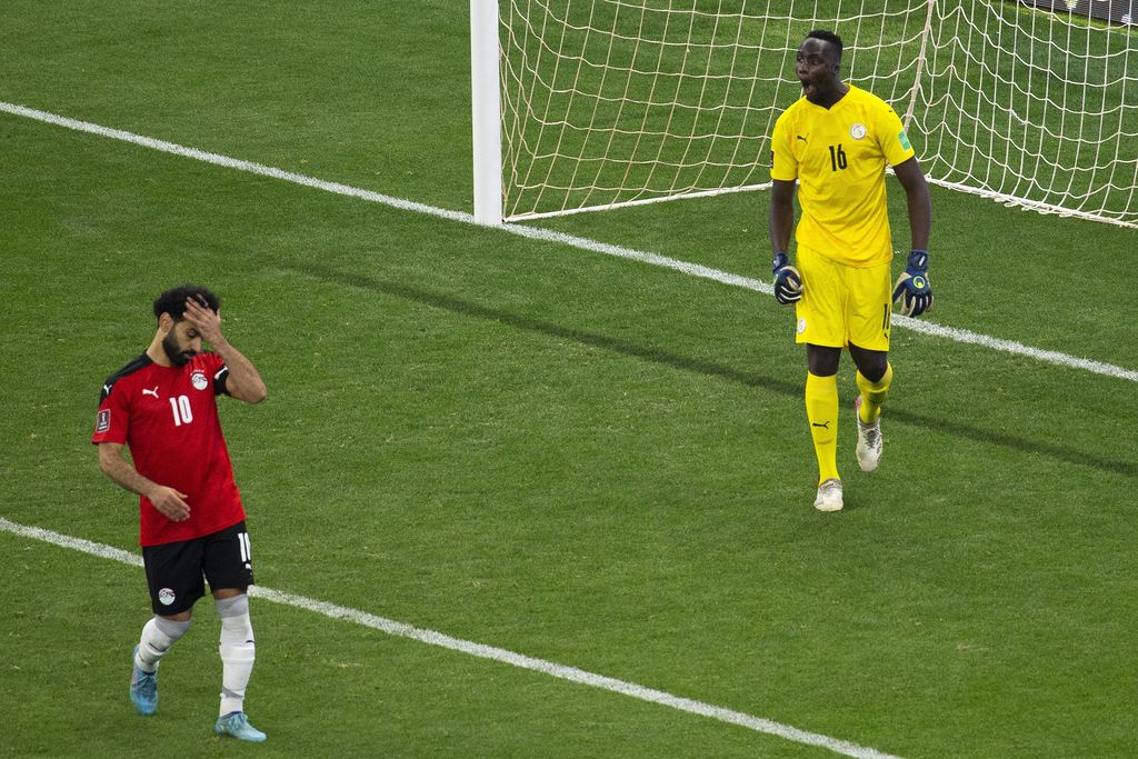 Egypt's Mohamed Salah, left, reacts after failing to score his penalty kick against Senegal's goalkeeper Edouard Mendy during the World Cup 2022 - Africa playoff soccer match between Senegal and Egypt at at Stade Me Abdoulaye Wade stadium in Dakar, Senegal, Tuesday, March 29, 2022. (AP Photo/Stefan Kleinowitz)