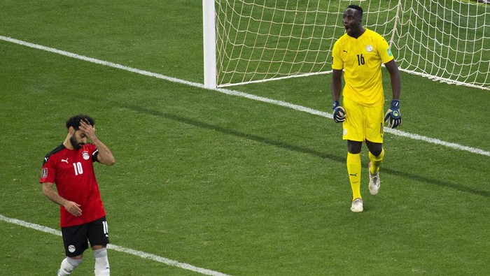 Egypts Mohamed Salah, left, reacts after failing to score his penalty kick against Senegals goalkeeper Edouard Mendy during the World Cup 2022 - Africa playoff soccer match between Senegal and Egypt at at Stade Me Abdoulaye Wade stadium in Dakar, Senegal, Tuesday, March 29, 2022. (AP Photo/Stefan Kleinowitz)