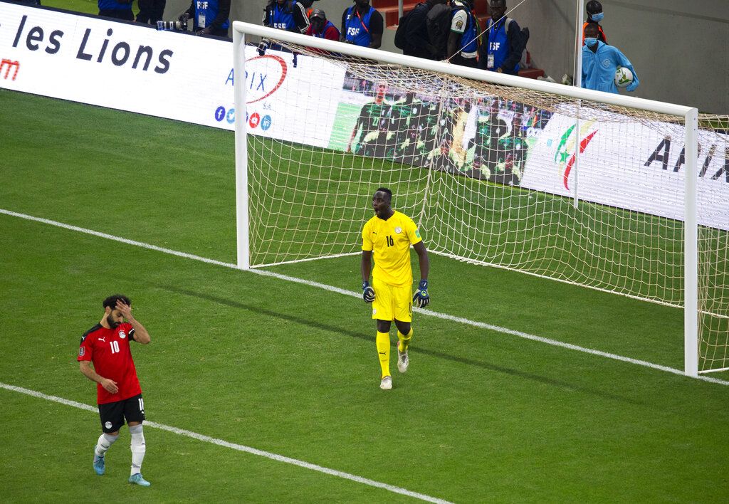 Egypt's Mohamed Salah, left, reacts after failing to score his penalty kick against Senegal's goalkeeper Edouard Mendy during the World Cup 2022 - Africa playoff soccer match between Senegal and Egypt at at Stade Me Abdoulaye Wade stadium in Dakar, Senegal, Tuesday, March 29, 2022. (AP Photo/Stefan Kleinowitz)