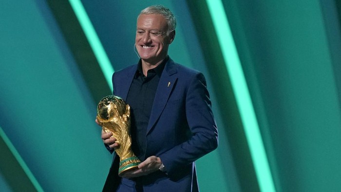 Reigning champions, Frances head coach Didier Deschamps carries the World Cup trophy onstage during the 2022 soccer World Cup draw at the Doha Exhibition and Convention Center in Doha, Qatar, Friday, April 1, 2022. (AP Photo/Darko Bandic)