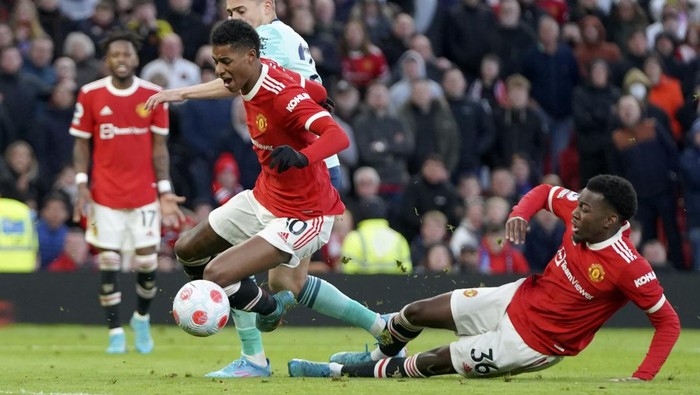 Manchester Uniteds Marcus Rashford falls over teammate Anthony Elanga, right, during the English Premier League soccer match between Manchester United and Leicester City at Old Trafford in Manchester, England, Saturday, April 2, 2022. (AP Photo/Jon Super)