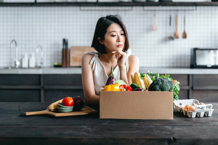 ilustrasi diet Young Asian woman received a box full of colourful and fresh organic groceries ordered online by home doorstep delivery. She is planning to cook a healthy meal in the kitchen at home. Healthy eating lifestyle