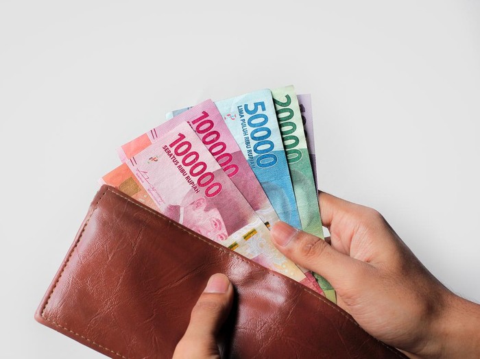 hand showing rupiah money from wallet isolated on white background