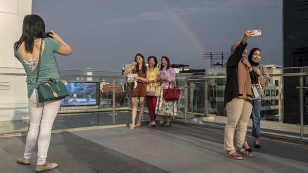 Pengunjung berfoto dengan latar belakang pelangi saat menanti waktu berbuka puasa di Sky Deck Sarinah, Jakarta, Rabu (6/4/2022). Kawasan tersebut menjadi salah satu destinasi baru bagi warga Jakarta dan sekitarnya untuk menanti waktu berbuka puasa atau ngabuburit bersama keluarga dan kerabat. ANTARA FOTO/Aprillio Akbar/rwa.