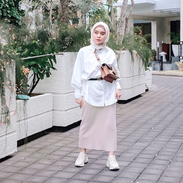 Lesty Kejora mengenakan oversized kemeja putih dipadukan dengan belt Gucci.