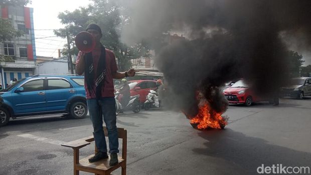 Mahasiswa Unismuh Makassar memblokade jalan dan bakar ban dalam aksi unjuk rasa menolak wacana jabatan presiden 3 periode (Muh Ishak Agus/detikSulsel)