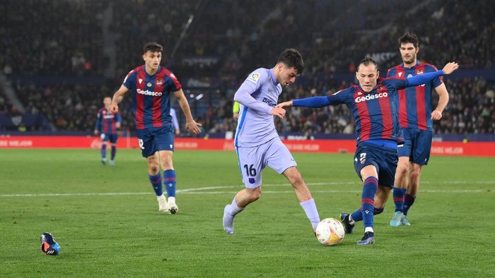 VALENCIA, SPAIN - APRIL 10: Pedri of FC Barcelona runs with the ball as their boot comes off whilst under pressure from Son of Levante during the La Liga Santander match between Levante UD and FC Barcelona at Ciutat de Valencia Stadium on April 10, 2022 in Valencia, Spain. (Photo by David Ramos/Getty Images)