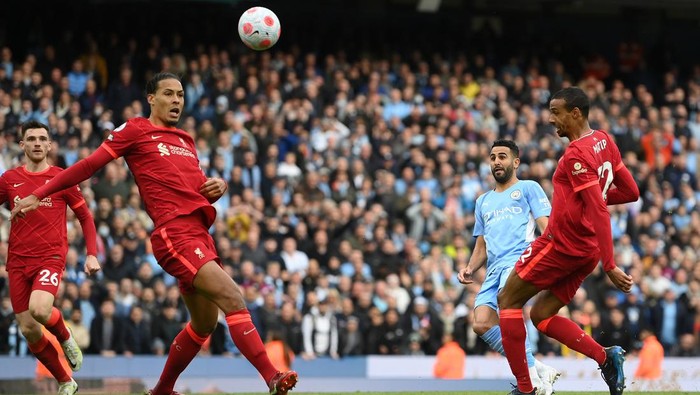 MANCHESTER, ENGLAND - APRIL 10: Riyad Mahrez of Manchester City shoots and misses whilst under pressure from Virgil van Dijk and Joel Matip of Liverpool during the Premier League match between Manchester City and Liverpool at Etihad Stadium on April 10, 2022 in Manchester, England. (Photo by Michael Regan/Getty Images)